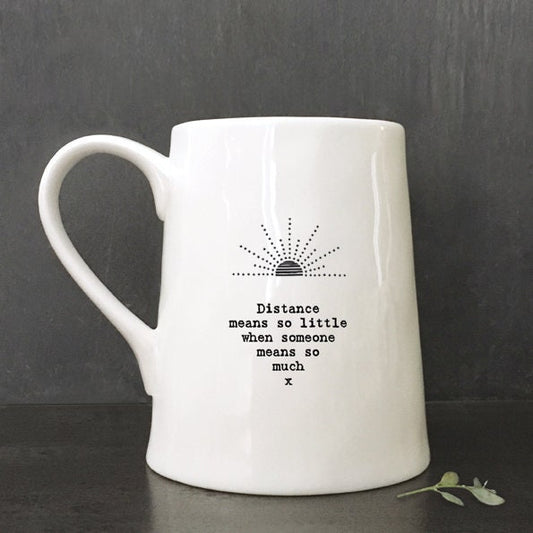 White mug with text and logo on a against a dark background