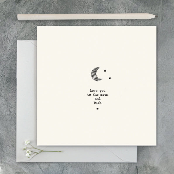 Greeting card with 'Love you to the moon and back' text and envelope on a gray surface
