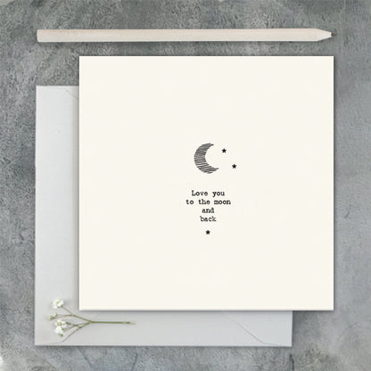 Greeting card with 'Love you to the moon and back' text and envelope on a gray surface