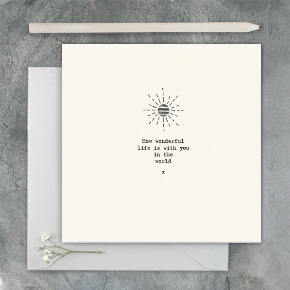 Greeting card with sun design and text on a gray surface