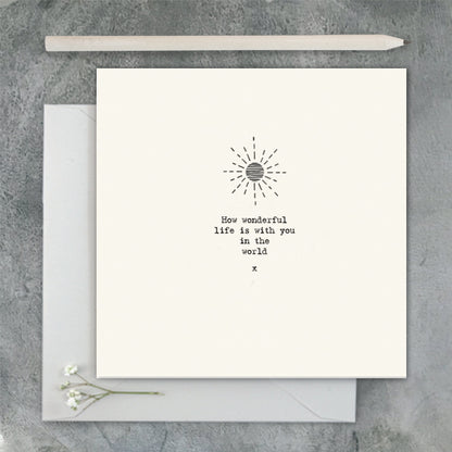 Greeting card with sun design and text on a gray surface