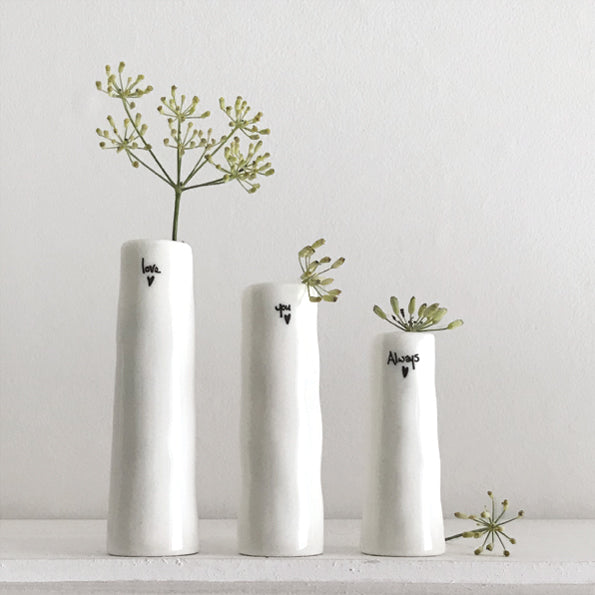 Three white vases with small plants on a light gray background