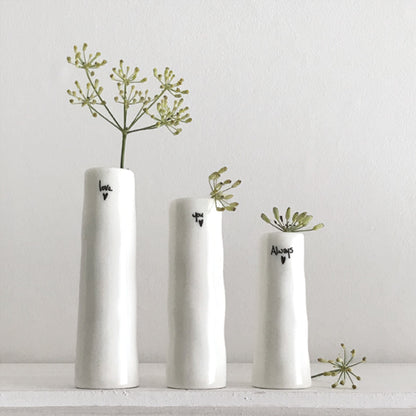 Three white vases with small plants on a light gray background