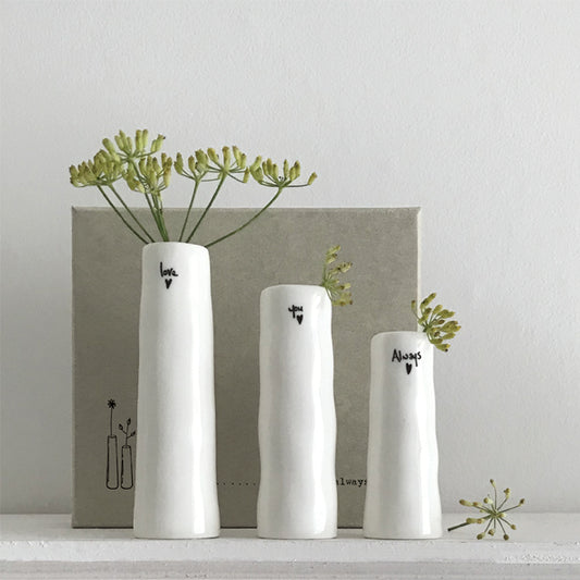 Three white vases with black text and greenery on a light gray background