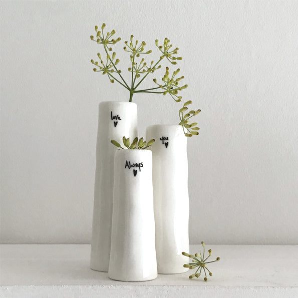 Three white vases with greenery on a light gray background