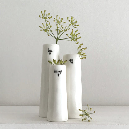 Three white vases with greenery on a light gray background