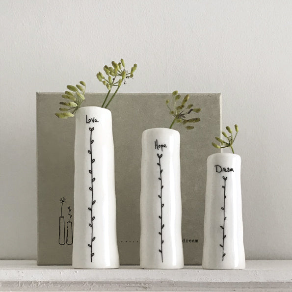 Three white vases with text and plant designs on a neutral background