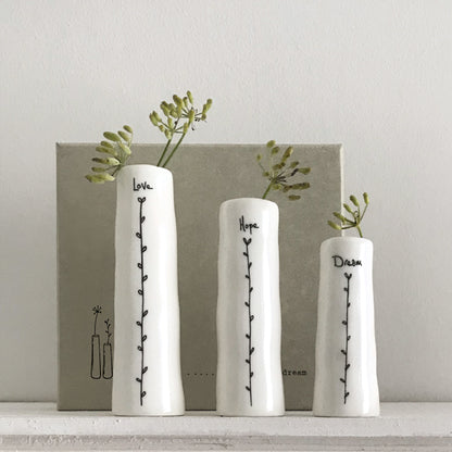 Three white vases with text and plant designs on a neutral background