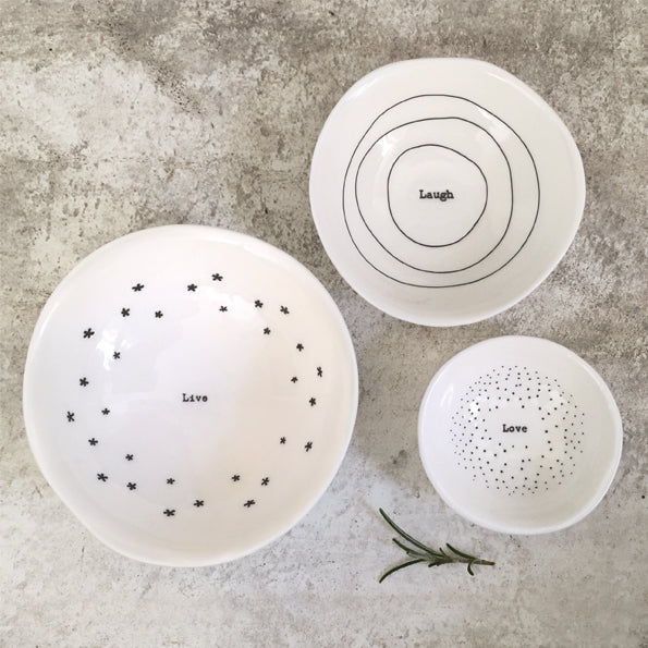 Three white ceramic plates with black text and patterns on a gray surface