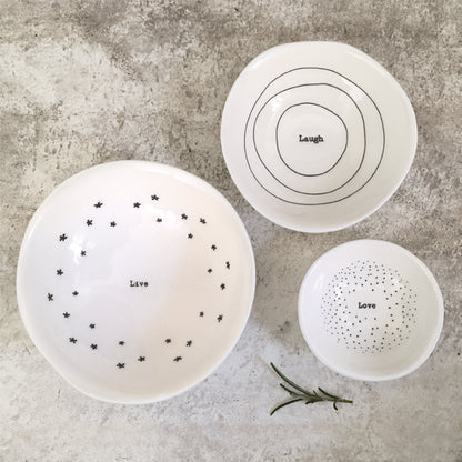 Three white ceramic plates with black text and patterns on a gray surface