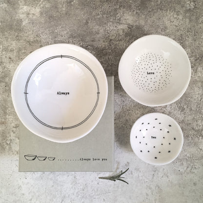 Set of white ceramic bowls with text on a gray surface