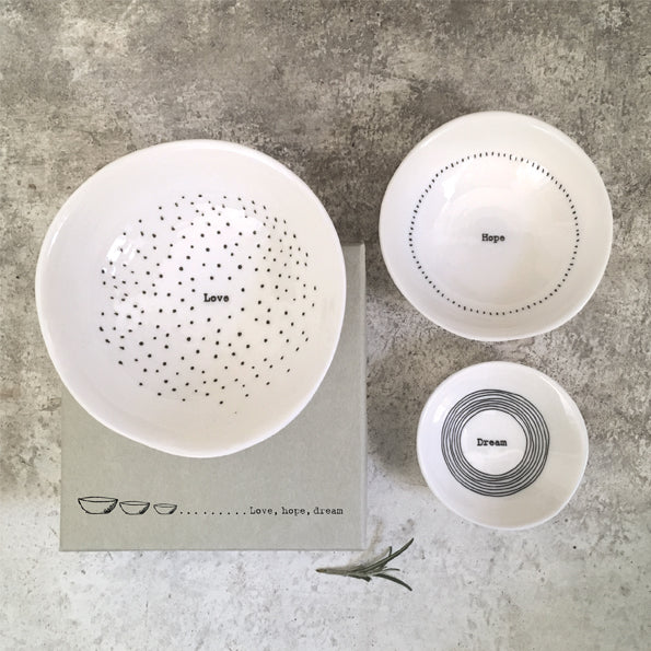 Set of white ceramic bowls with text on a textured surface