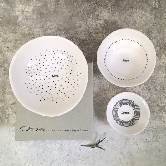 Set of white ceramic bowls with text on a textured surface