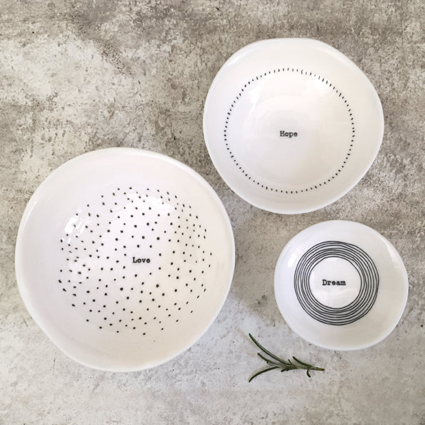 Three white ceramic bowls with text on a gray surface
