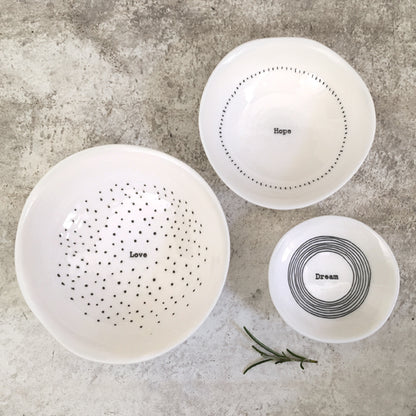 Three white ceramic bowls with text on a gray surface