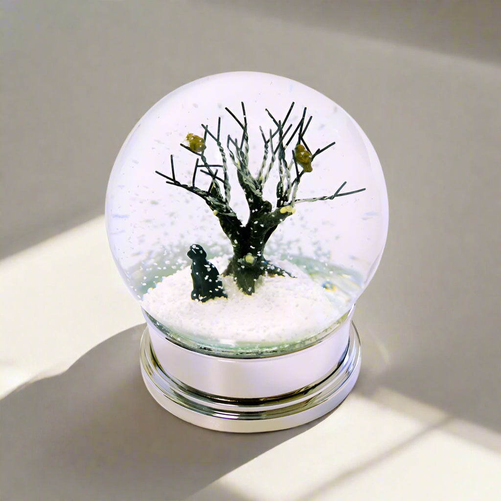 Glass snow globe with a tree inside on a white background