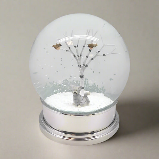 Snow globe with a tree and animal figure inside on a white background