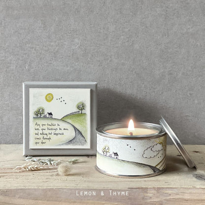 Candle in a tin with a decorative label on a wooden surface, featuring the brand 'Lemon & Thyme'.