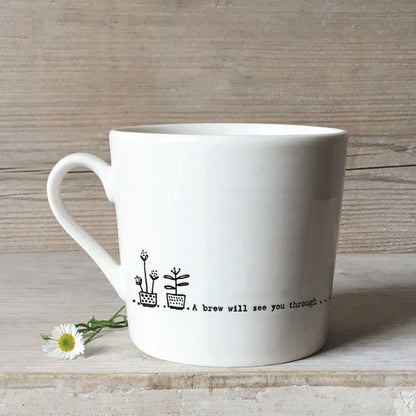 White mug with a black text and flower design on a wooden background