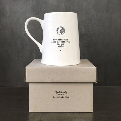 White mug with a black text and globe design on a dark background