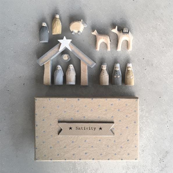 Wooden nativity set with stable and figures against a gray background
