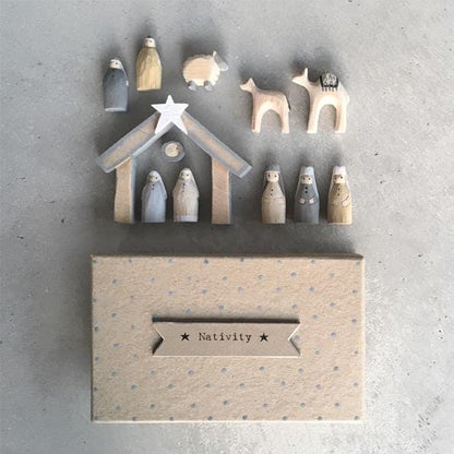 Wooden nativity set with stable and figures against a gray background