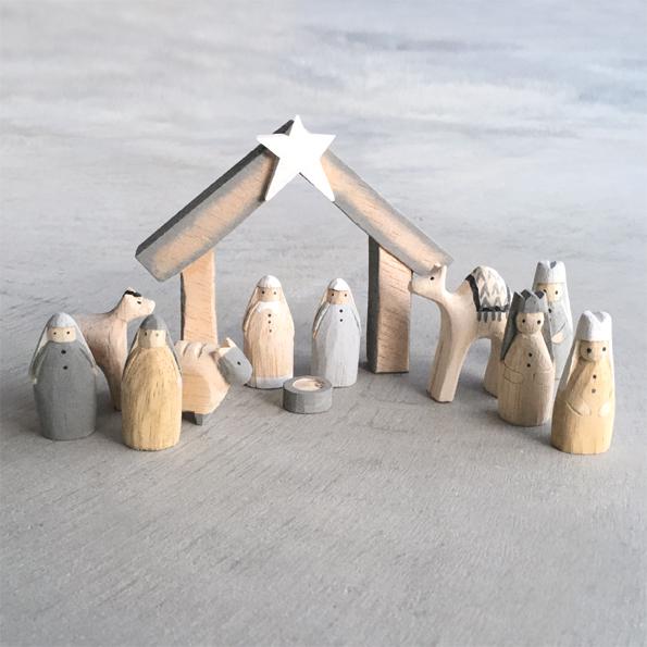 Wooden nativity set with stable and figures against a gray background