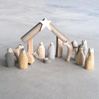Wooden nativity set with stable and figures against a gray background