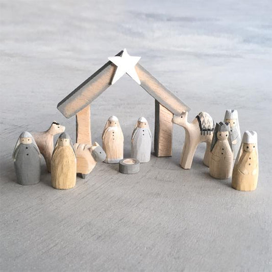 Wooden nativity set with stable and figures against a gray background