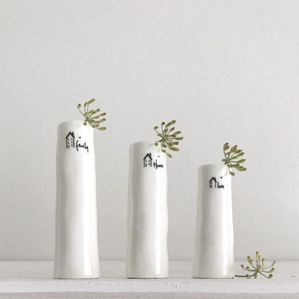 Three white vases with decorative text and greenery on a light gray background