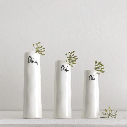 Three white vases with decorative text and greenery on a light gray background
