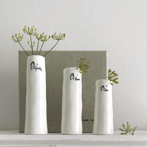 Three white vases with decorative text and greenery on a light gray background