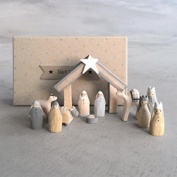 Wooden nativity set with stable and figures on a gray background
