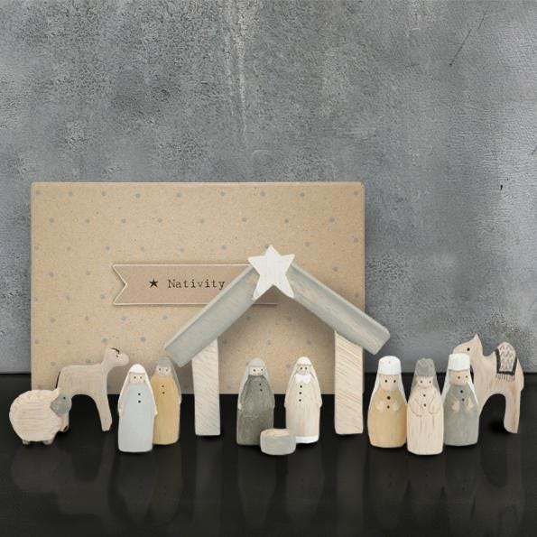 Wooden nativity set with stable and figures against a gray background