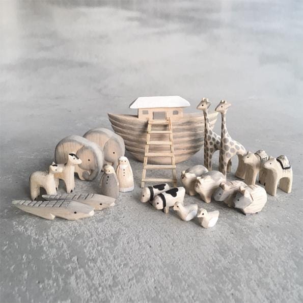 Wooden toy set including a Noah's ark and various animals on a gray surface