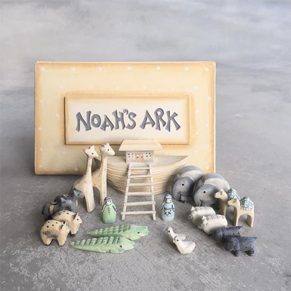 Set of wooden toy animals and structures on a gray surface