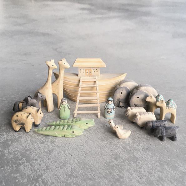Set of wooden toy animals and structures on a gray surface