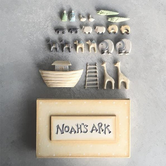 Set of wooden toy animals and structures on a gray surface